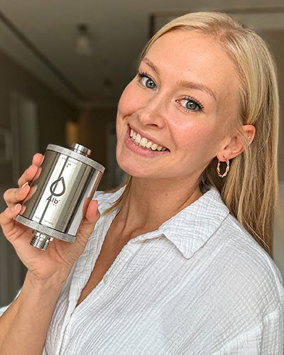 Lächelnde Frau hält ein Alb Filter Wasserfiltergehäuse in der Hand