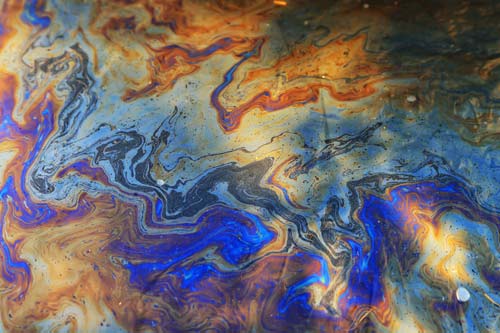 Ölteppich auf einer Wasseroberfläche als Sinnbild für Wasserverschmutzung durch industrielle Einleitungen und Altlasten.