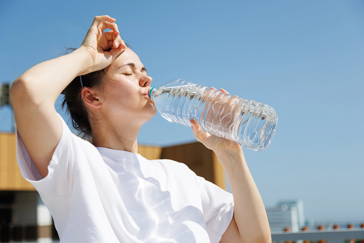 Frau trinkt Wasser bei Hitze: Der Schweißverlust kann bei hoher Temperatur und Aktivität mehrere Liter pro Tag betragen.