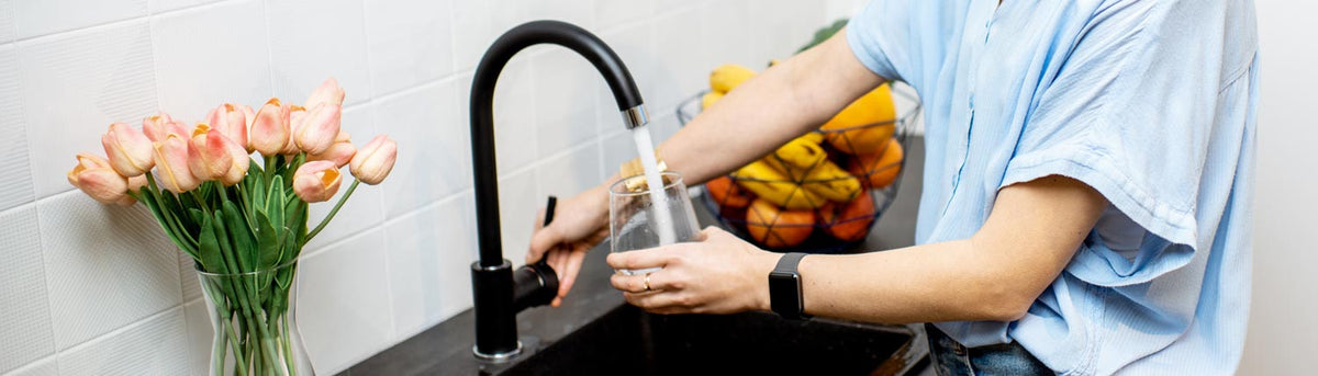 Frau füllt ein Glas Leitungswasser am Wasserhahn: In Deutschland gilt Leitungswasser als eines der am strengsten kontrollierten Lebensmittel.