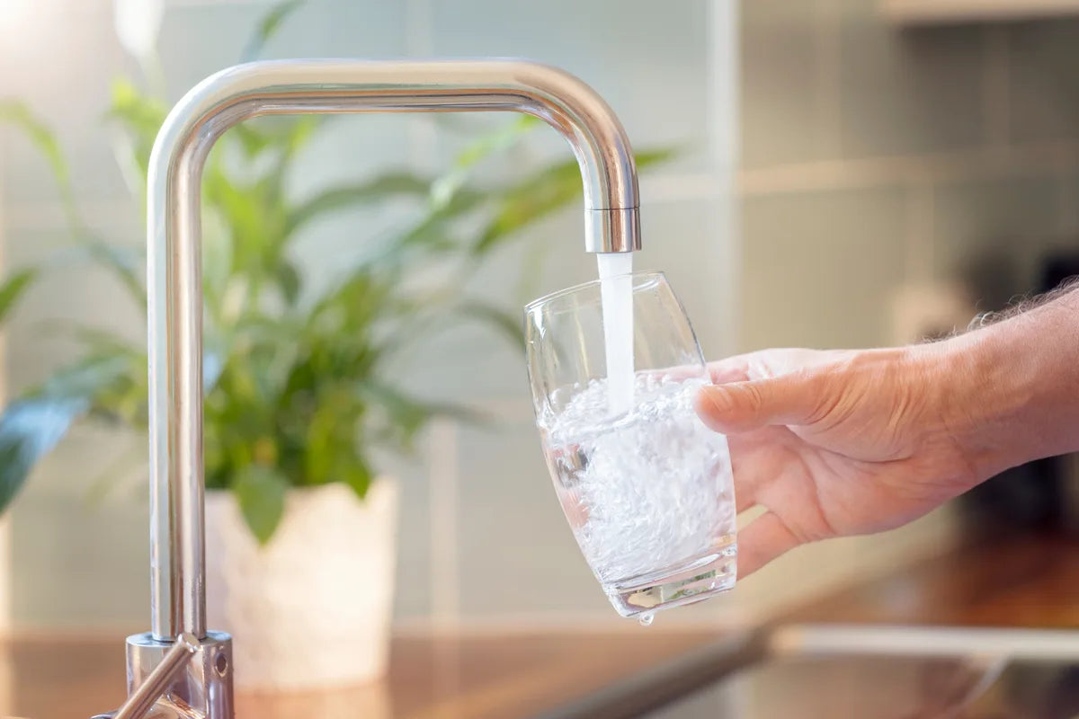 Glas wird am Wasserhahn mit Leitungswasser gefüllt