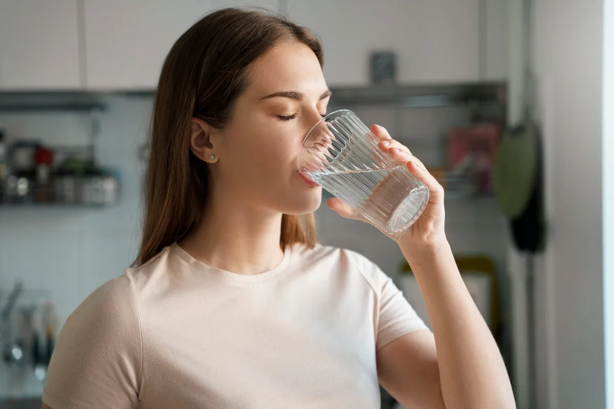 Junge Frau trinkt ein Glas Wasser in der Küche