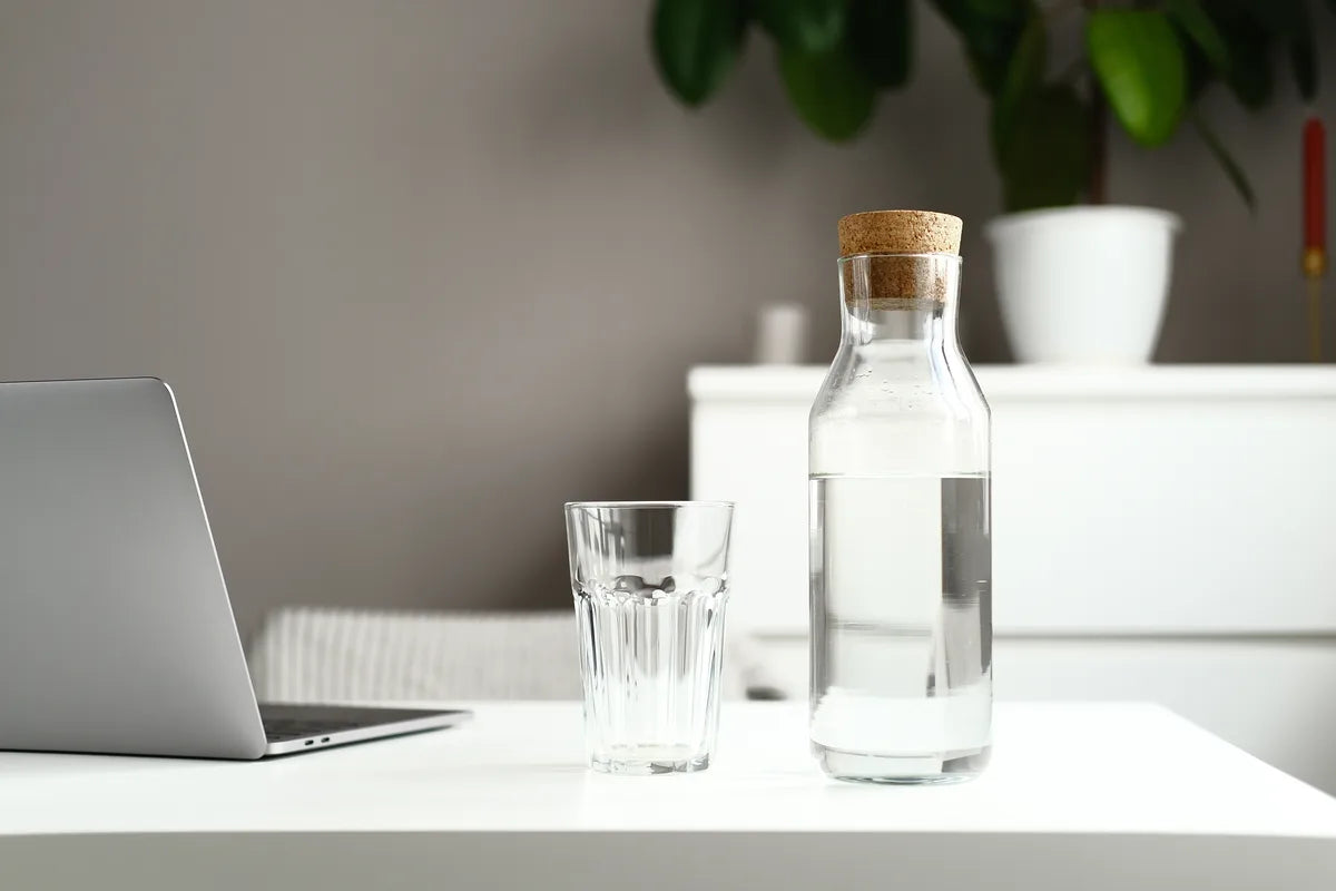 Wasserflasche und Glas Wasser auf dem Tisch