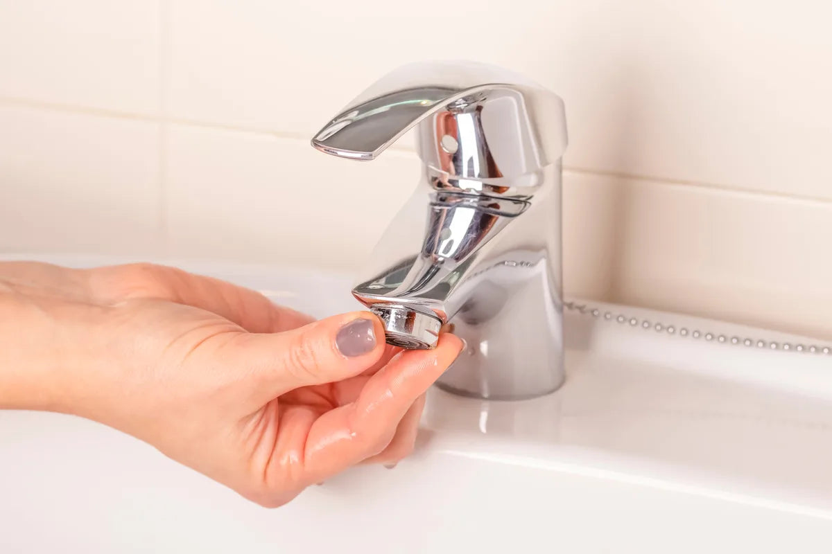Hand schraubt den Perlator vom Wasserhahn ab