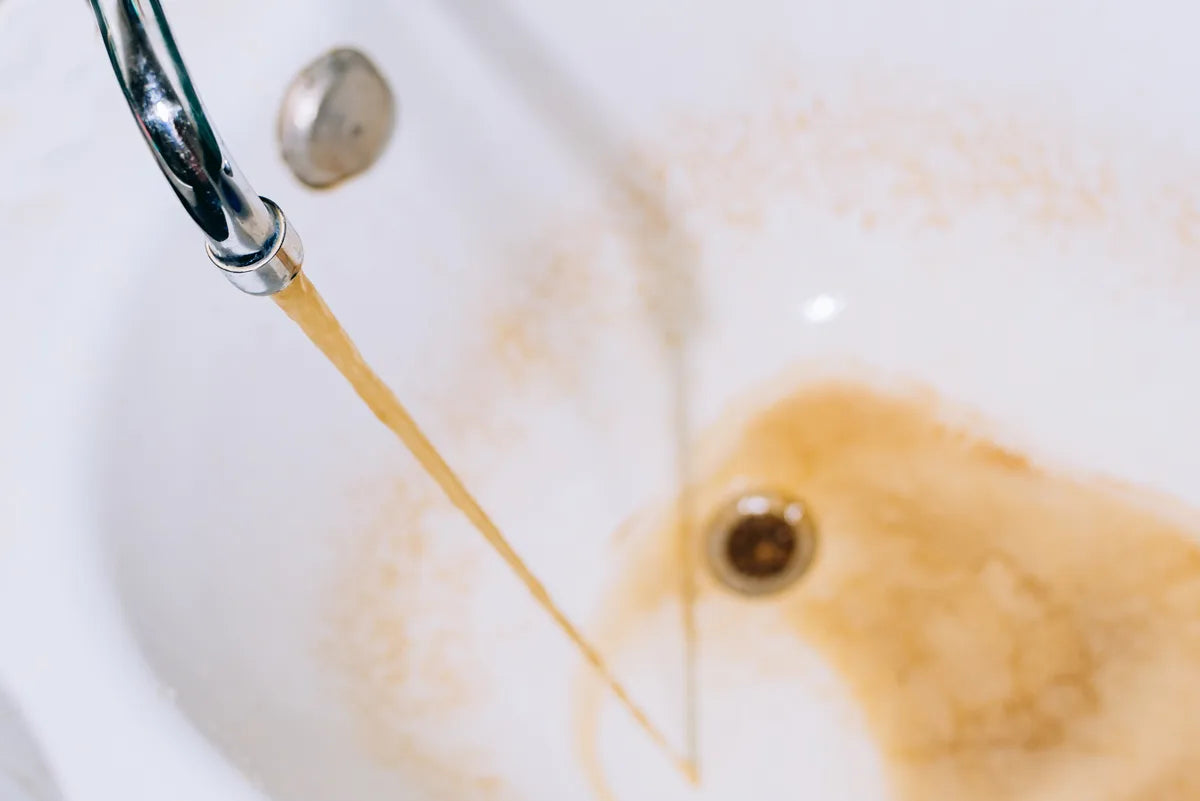 Rostbraunes Wasser läuft aus dem Wasserhahn in die Badewanne