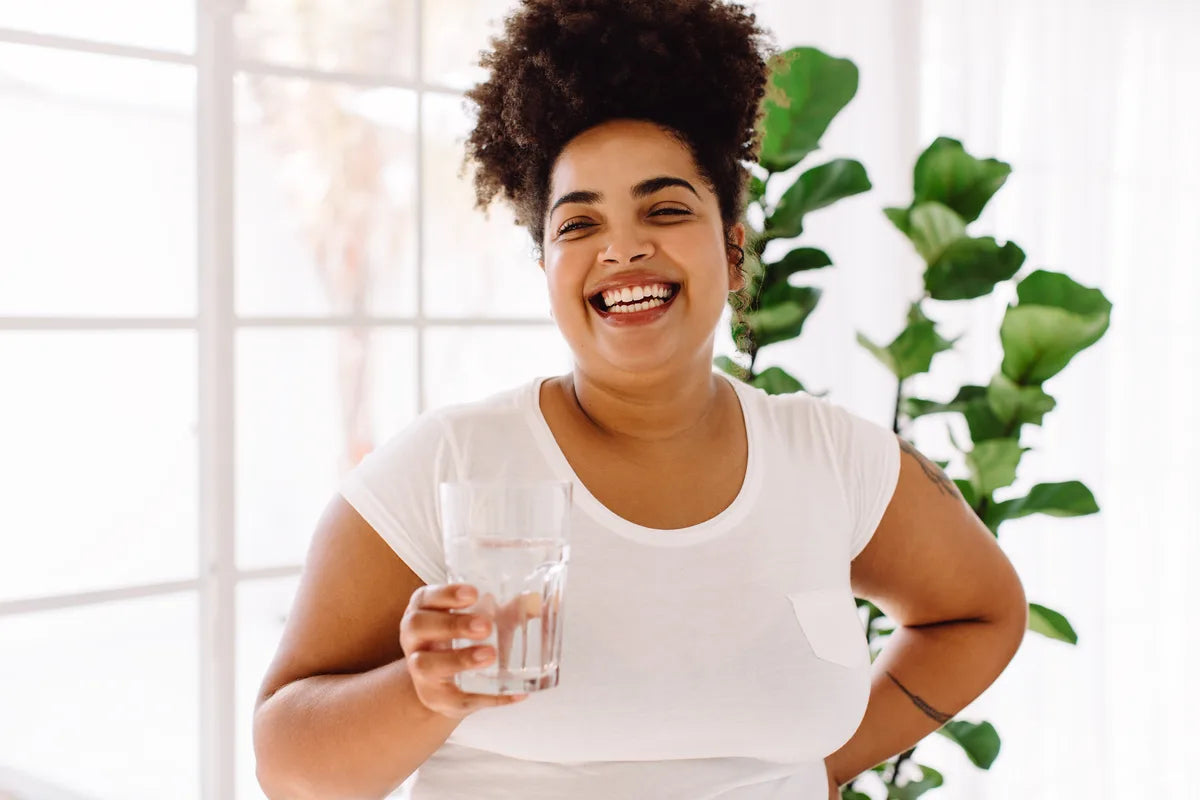 Frau mit einem Glas Wasser zu Hause