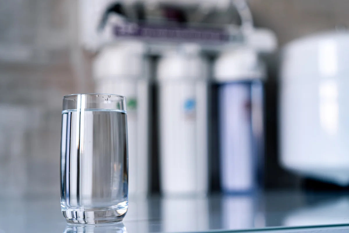 Glas Wasser vor einer Untertisch-Filteranlage